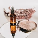 Amber glass bottle with dropper and botanical reflection on mirror, ideal for skincare ads.