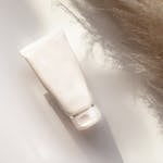 Elegant white cosmetic tube with shadows on a neutral background, suitable for beauty product presentations.