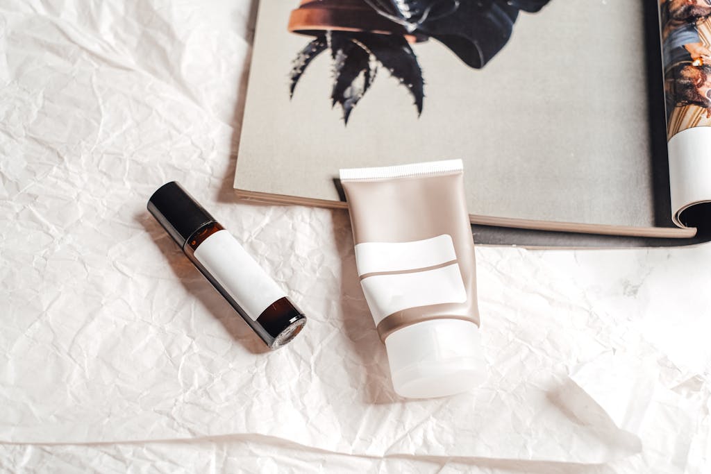 Flat lay of skincare products on textured paper with an open magazine, showcasing a stylish aesthetic.